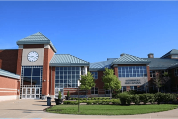 The front of a brick building with a clock on the left side.